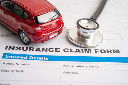 Stethoscope with red car on Insurance claim accident car form, Car loan, insurance and leasing time concepts.の写真素材