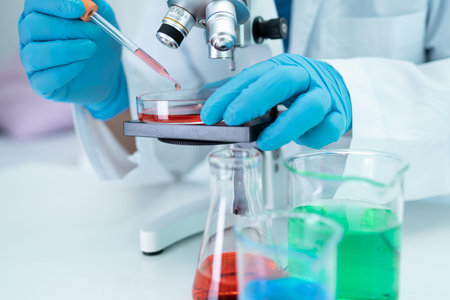 Asian scientist biochemist or microbiologist working research with a microscope in laboratory.