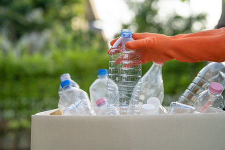 Asian woman volunteer carry water plastic bottles into garbage box trash in park, recycle waste environment ecology concept.の写真素材