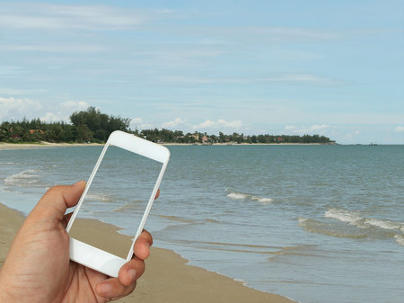 hand holding the smartphone on sea background