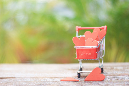 small supermarket cart full of Valentines Day hearts on a blurred background.