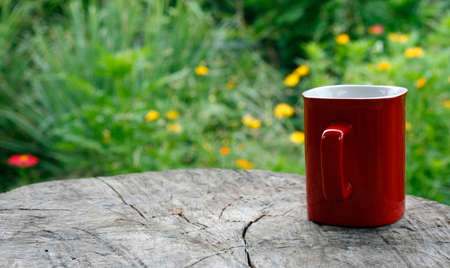 Red mug coffee on wooden tabletop against blurred greenの写真素材