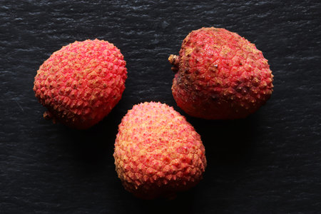Photography of three isolated litchis on slate background for food illustrations