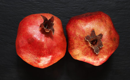 Photography of two whole pomegranates on slate background for food illustrations