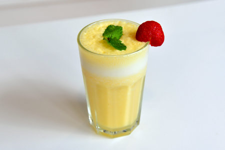 Healthy yellow smoothie with straw in a jar mug isolated on white