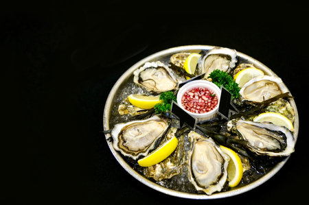 Fresh oysters on a plate with ice and lemon slicesの写真素材