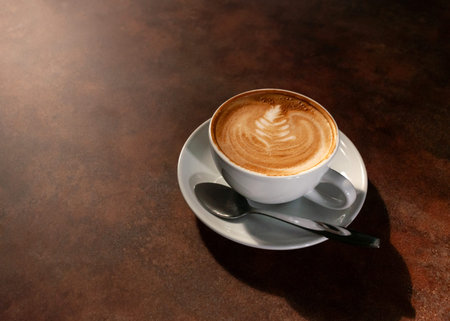 Cup of hot latte art in afternoon light on wooden table