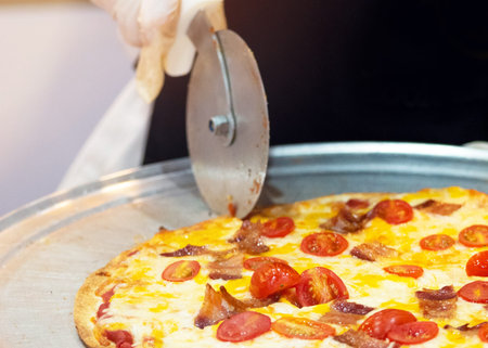Slicing Fresh Made Italian Pizza, Closeup hand of chef cutting pizza in kitchen
