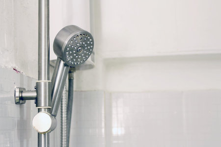 Bath shower on white tile wall