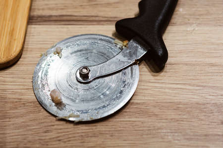 Delicious fresh pizza, closeup of pizza cutter on italian pizza on wooden tableの写真素材