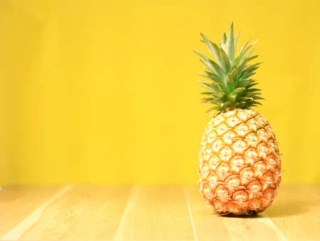 Ripe pineapple on a yellow wooden backgroundの写真素材