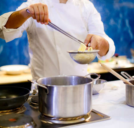 Chef cooking spaghetti in the kitchenの写真素材