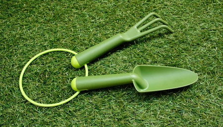 Gardening trowel and rake on grass