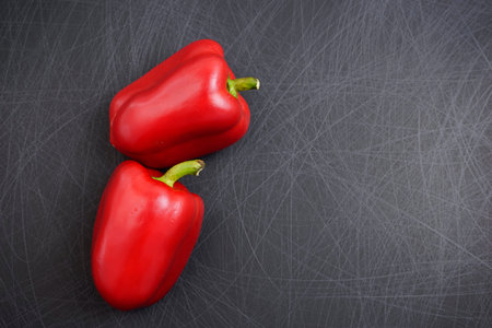 Close-up. Colorful, fancy red bell or sweet peppers flat lay on grunge scratched texture black...