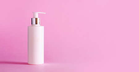 White bottle of moisturizing lotion on pink background with copy space. Minimalism style. Skin care, body treatment, beauty conceptの写真素材