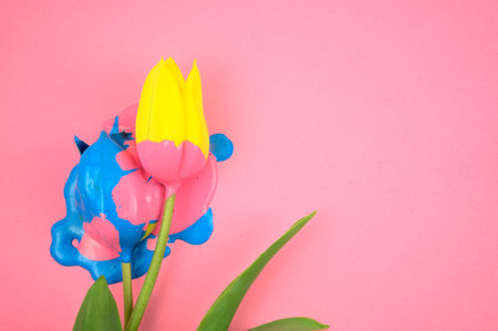 Colorful acylic and yellow flower, tulip flat lay on clear pink background. Dripping vivid candy ink...
