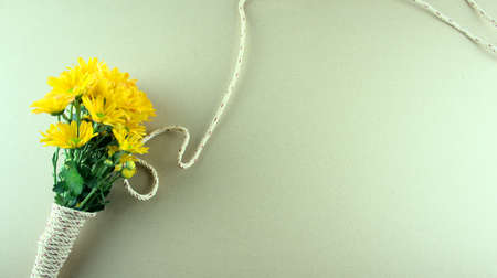 Flat lay of a bouquet of yellow mums or Chrysanthemum flowers, binding with gray white rope on grey background. Genus Chrysanthemum is in the family Asteraceae. Any celebrations, flat lay with flowers concept. Copy space. Minimal style.の写真素材