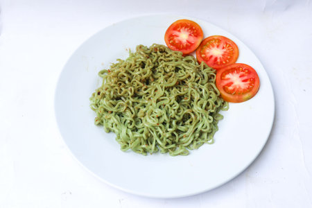 green noodles, or Spinach pasta , Zucchini raw vegan pasta dip, and tomatoes on plate.の素材
