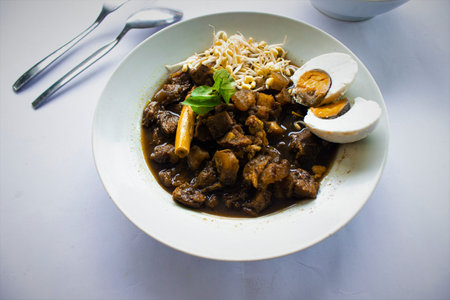 Rawon or Nasi Rawon/Rawon Rice is traditional Indonesian beef black soup served with sprouts, salted eggs, kluwek seasoning. From east java. Isolated on black backgroundの素材