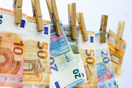 euro banknotes hung on a clothesline with clothespins white background for copy spaceの素材