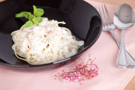 spagetthi white sauce with mushroom in black dish on pink tableclothの写真素材