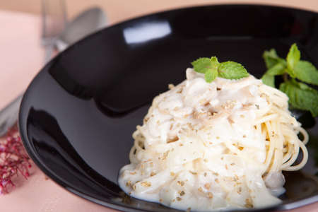 spagetthi white sauce with mushroom in black dish on pink tableclothの写真素材