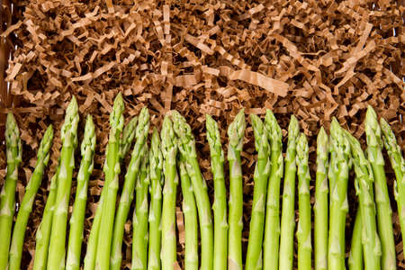 Bunch of fresh green asparagus on brown shredded paperの写真素材