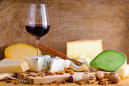 Still life glass of red wine and cheese plate on a vintage wooden backgroundの写真素材