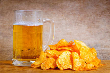 Beer mug and potato chips on a wooden backgroundの写真素材