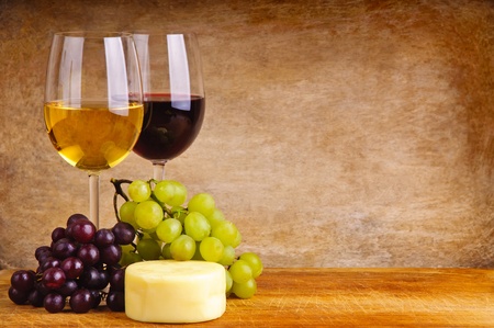 still lired and white wine, cheese and grapes on a wooden background with copy spaceの写真素材