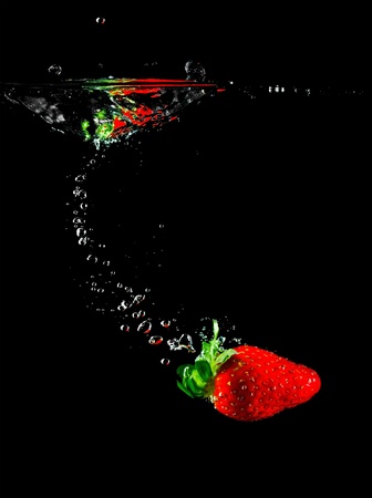 Strawberry fruit sinking in water on a black backgroundの写真素材