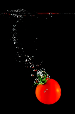 Fresh tomato sinking in water on a black backgroundの写真素材