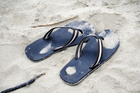 pair of black flip flops in sand beachの写真素材