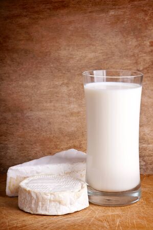 glass of fresh milk with brie and camembert chesse on a wooden backgroundの写真素材