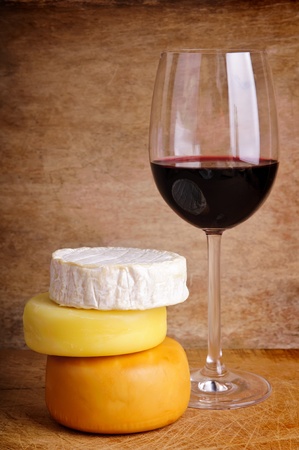 glass of red wine with different cheese on a vintage wooden backgroundの写真素材