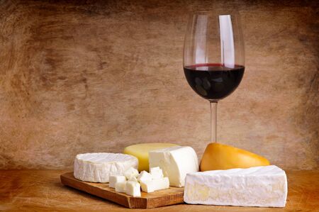 group of different cheese with glass of red wine on a vintage wooden backgroundの写真素材