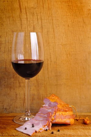 glass of red wine with smocked ham on a wooden backgroundの写真素材