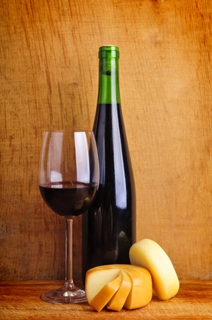 still life composition with glass and bottle of red wine and cheeseの写真素材