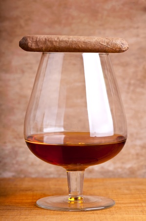 glass of cognac and cigar against a wooden backgroundの写真素材