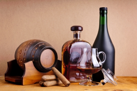 cuban cigars and cognac or brandy in glass, bottles and barrel on a wooden backgroundの写真素材