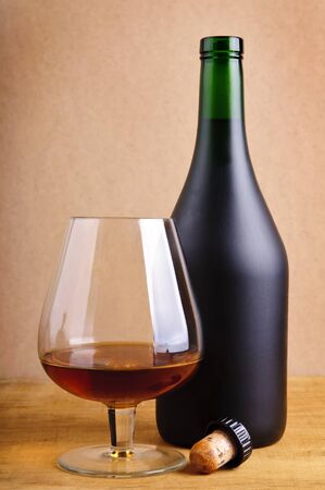 glass and bottle of cognac with cork on a wooden backgroundの写真素材