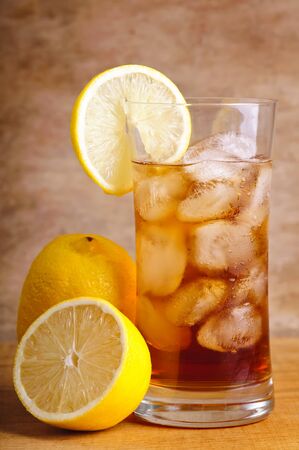 glass of ice tea with lemon fruits on a wooden backgroundの写真素材