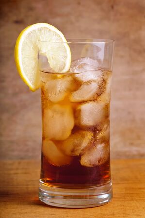 glass of ice tea with lemon slice on a vintage wooden backgroundの写真素材