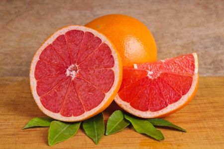 fresh pink grapefruit and leafs on a wooden backgroundの写真素材