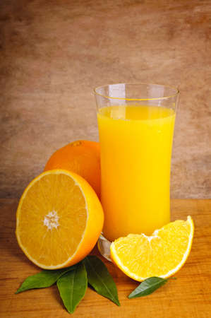 glass of fresh orange juice and oranges on a wooden backgroundの写真素材