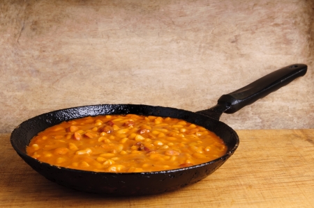 traditional homemade meal with beans and sausages in a pan on a wooden backgroundの写真素材