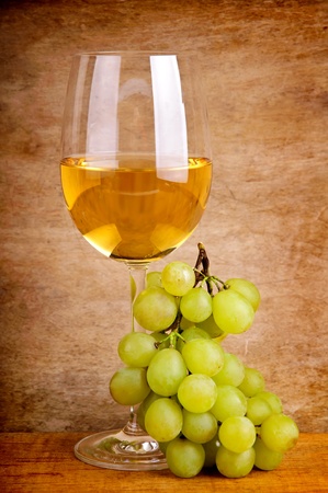 glass of white wine and grapes on a vintage wooden backgroundの写真素材