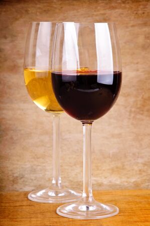 two glasses of red and white wine on a wooden backgroundの写真素材