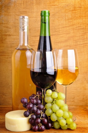 still life with red and white wine, grapes and cheese on a wooden backgroundの写真素材