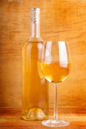 glass and bottle of white wine on a wooden backgroundの写真素材